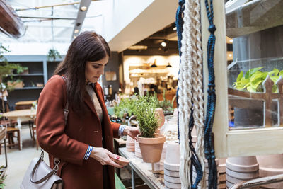 Female customer looking at potted plant in store