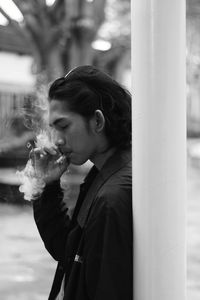 Side view of young man smoking cigarette