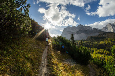 Dirt road passing through mountains against cloudy sky