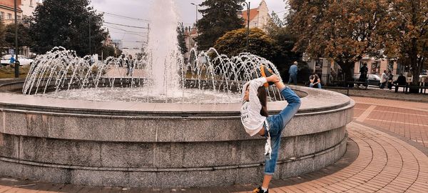 Full length of woman walking by fountain in city