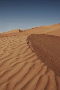 Sand dunes in desert against clear sky