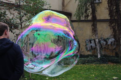 Rear view of man standing by large bubble at park