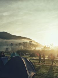 People and tents on field during sunny day