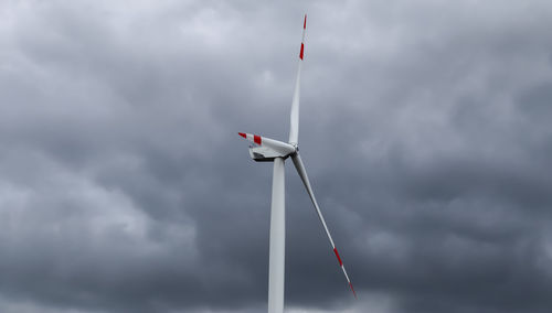 Low angle view of wind turbine against cloudy sky