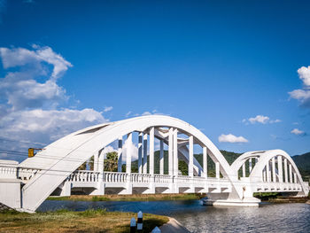 Arch bridge over river against cloudy sky