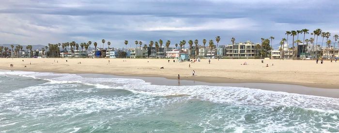 Panoramic view of beach, palms and buildings against sky