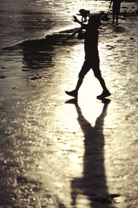 Low section of silhouette woman standing on beach