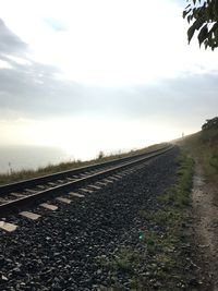 Surface level of railroad tracks on field against sky