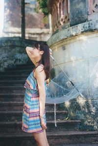 Young woman standing by tree