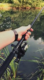 Man holding fishing rod by lake