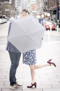 Couple engaging in intimate embrace behind the concealment of an umbrella