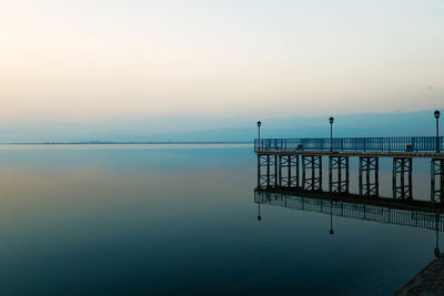 Pier by calm lake against sky