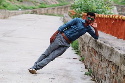 Full length of man leaning on retaining wall