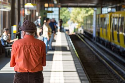 Rear view of man standing on railroad station platform