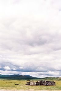 Scenic view of grassy field against cloudy sky