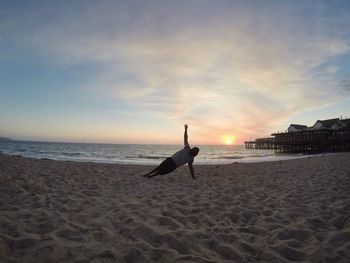 Man on beach against sky during sunset