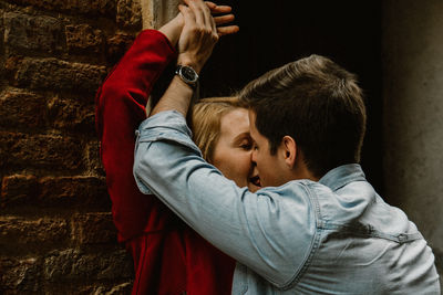 Side view of couple kissing against wall
