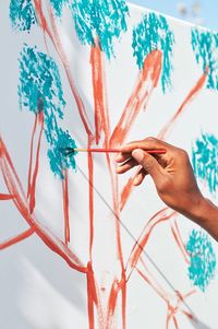 Close-up of hand holding painting on wall