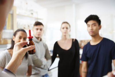 Cropped image of mature female teacher showing solution while explaining to young multi-ethnic students in laboratory