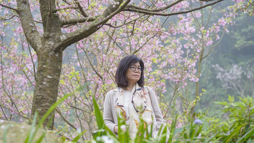 Portrait of woman standing by flower tree