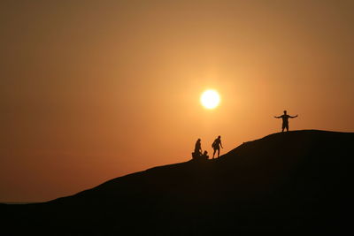 Silhouette people on mountain against sky during sunset