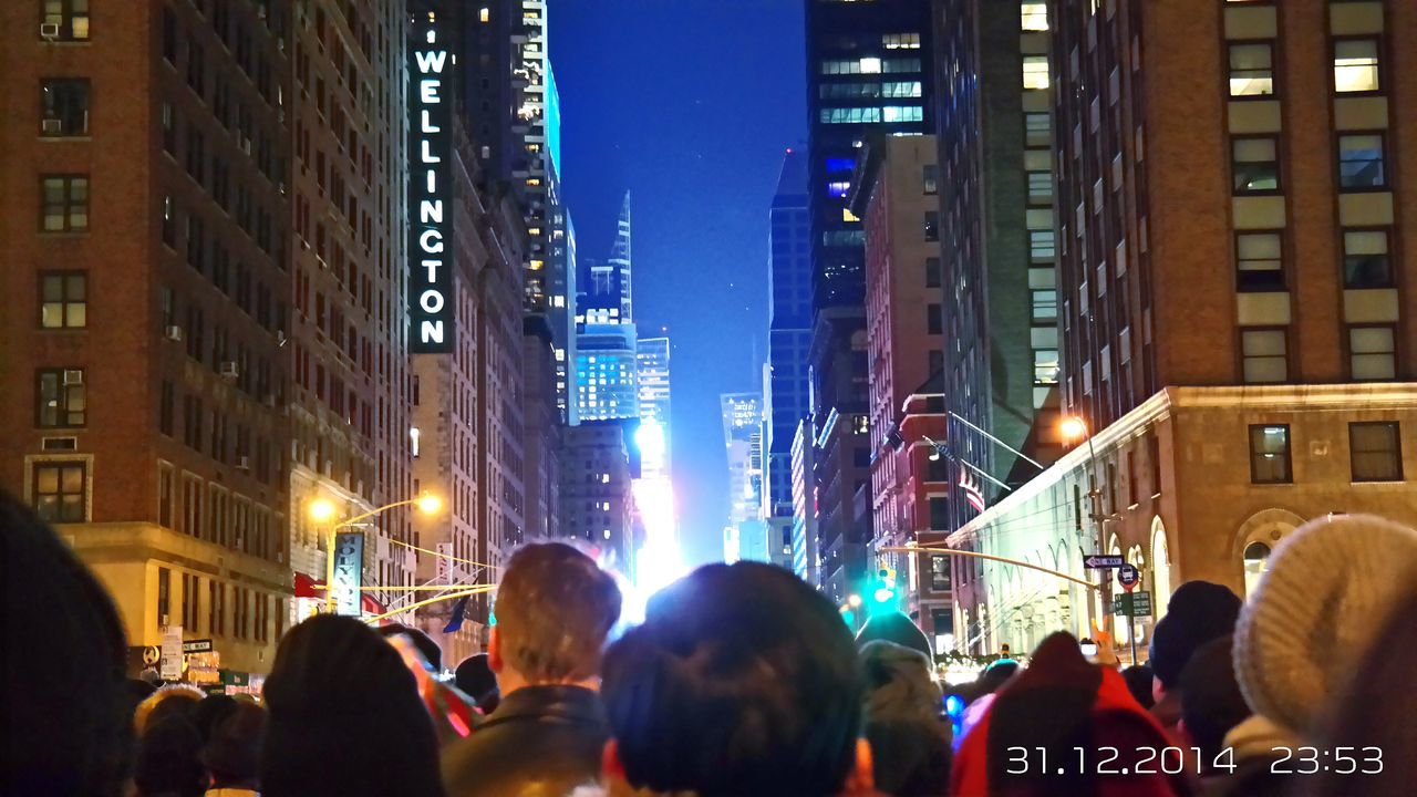 building exterior, architecture, built structure, illuminated, large group of people, city, men, lifestyles, night, person, city life, leisure activity, crowd, street, skyscraper, building, group of people, city street, lighting equipment