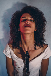 Portrait of young woman standing against wall