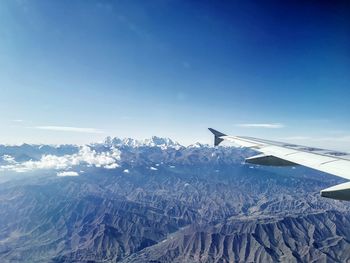 Airplane flying over snowcapped mountains against sky