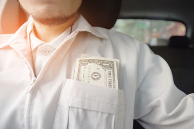 Midsection of man with paper currency in pocket