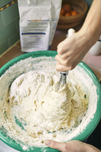 Cropped image of woman whisking batter in container at kitchen counter