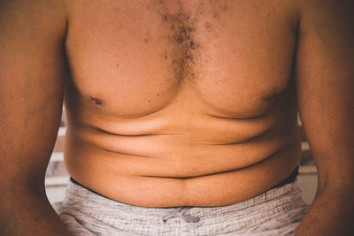 Midsection of shirtless man at home