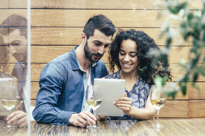 Young couple holding mobile phone while sitting on table