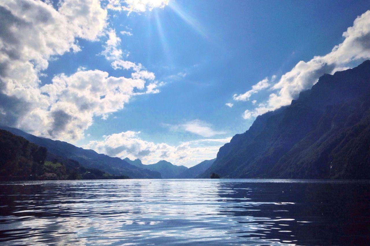 mountain, water, mountain range, tranquil scene, scenics, tranquility, sky, beauty in nature, waterfront, lake, reflection, nature, cloud - sky, sunlight, idyllic, cloud, sunbeam, river, sun, outdoors