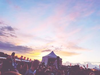 People at music concert against sky during sunset