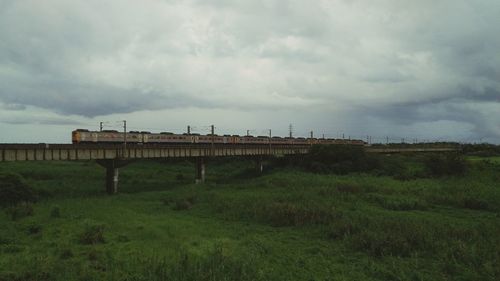 Scenic view of grassy field against cloudy sky