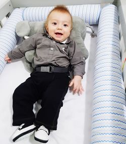 High angle view of smiling baby boy lying on bed