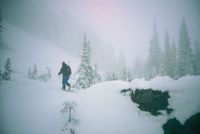 Man skiing on snow covered mountain against sky