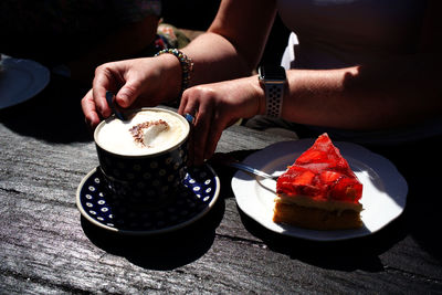 Midsection of woman with coffee cup on table