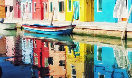 Multi colored boats moored in lake against buildings