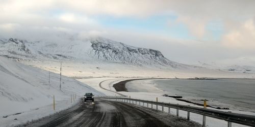 Road amidst snowcapped mountains against sky during winter