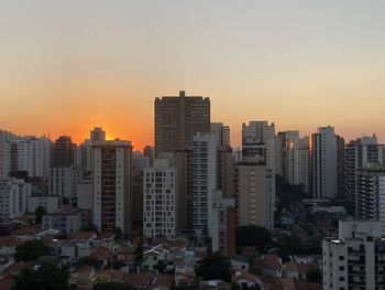 Buildings in city against clear sky during sunset
