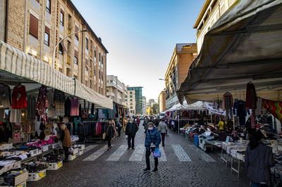 People walking on street amidst buildings in city