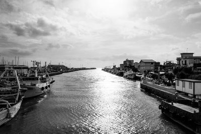 Boats moored in river at city against sky