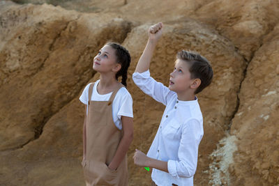 Portrait of smiling friends standing on rock