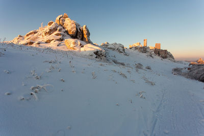 Rocks on snow covered land against sky