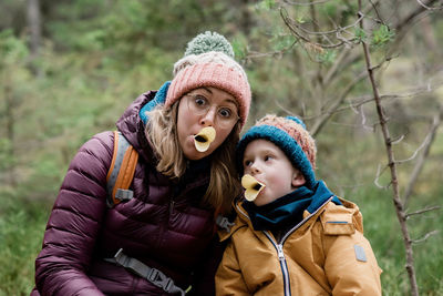 Mom and son making silly faces with food whilst hiking in winter