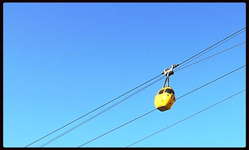Low angle view of power lines against clear blue sky