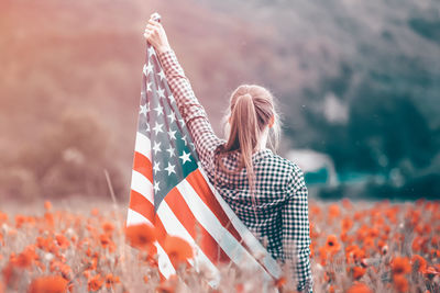 Rear view of woman with umbrella sitting outdoors