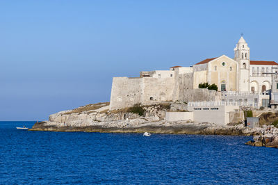 Building by sea against blue sky