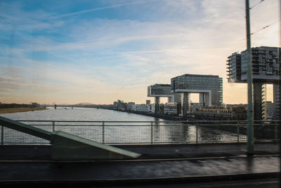 Bridge over river by buildings in city against sky